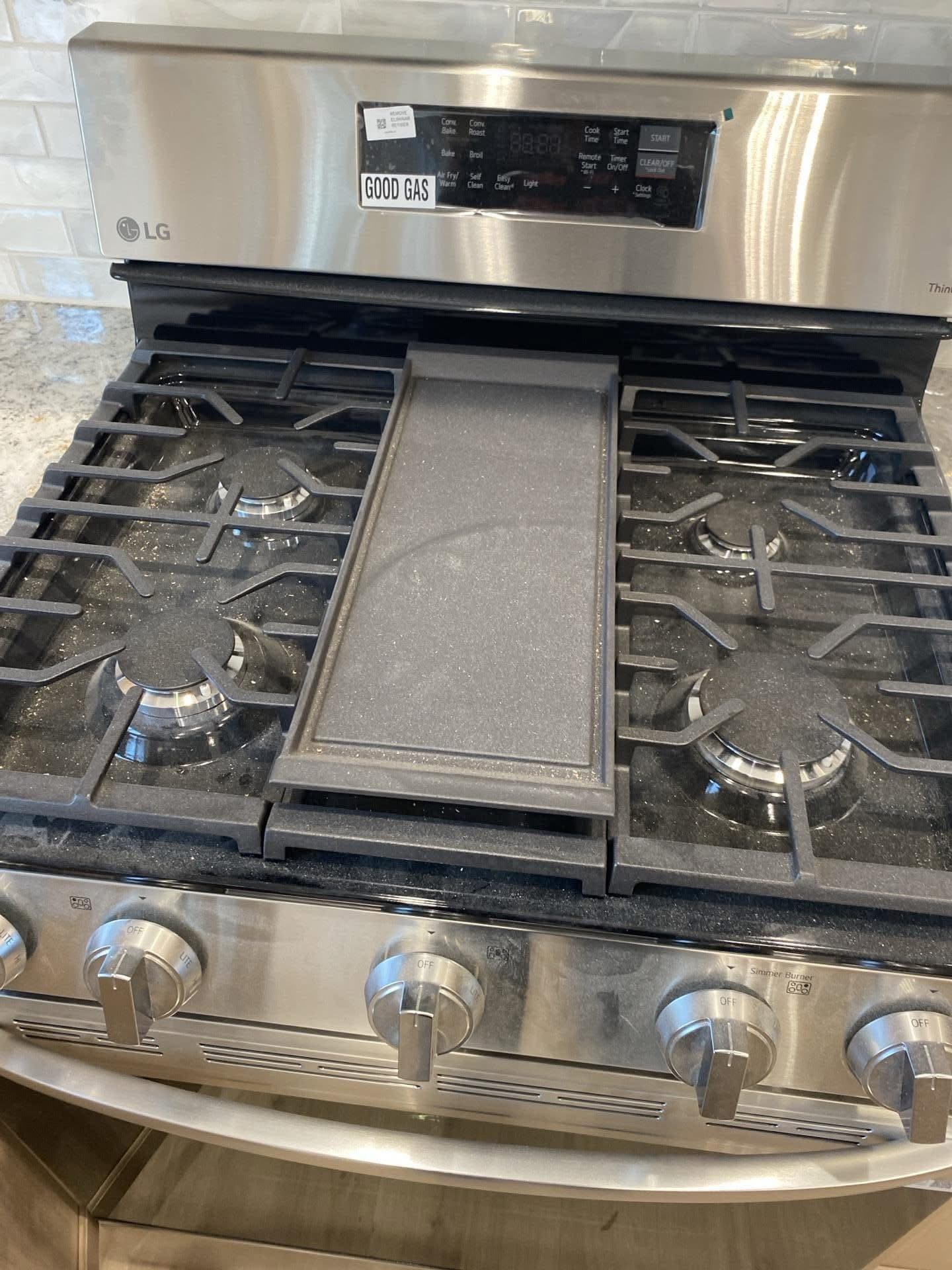 Stainless steel LG gas stove with four burners and a central rectangular griddle plate.